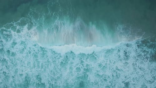 Aerial top view of ocean turquoise blue waves with white wash. Big power tides, creating foam.