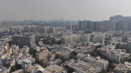 Drone shot revealing a compact city landscape with numerous apartment complexes and streets,