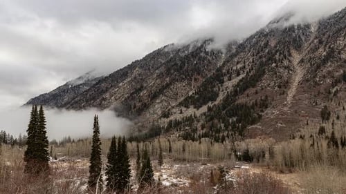 Time-lapse of clouds swirling around high mountain peaks and fog rolling up from the valley. Shot i