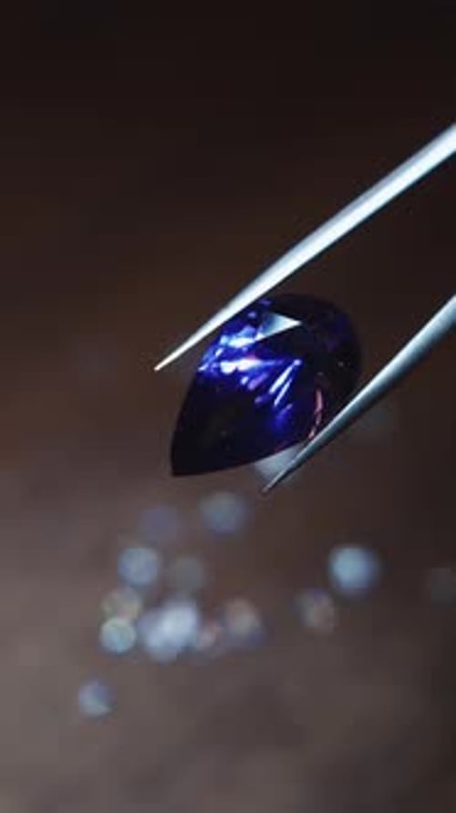 A Person is Holding a Gemstone in a Pair of