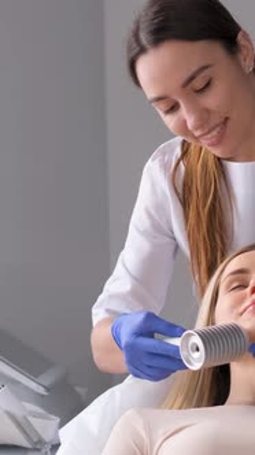 A Professional Beautician with a Patient During a Facial Treatment Procedure in a Cosmetology Clinic