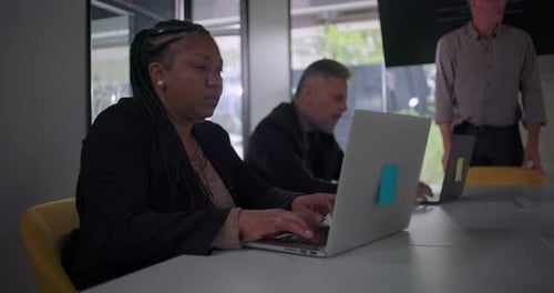 Diverse Team Working on Laptops in Modern Office