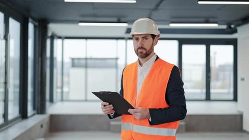 Confident Engineer in Modern Office with Clipboard and Safety Vest