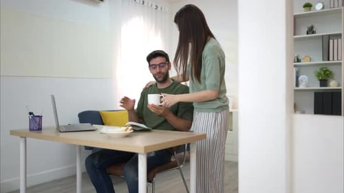 Caring Woman Brings Coffee to Man Working at Home