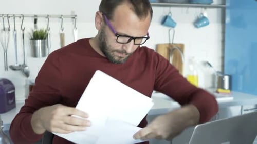 Man Working from Home with Laptop and Documents