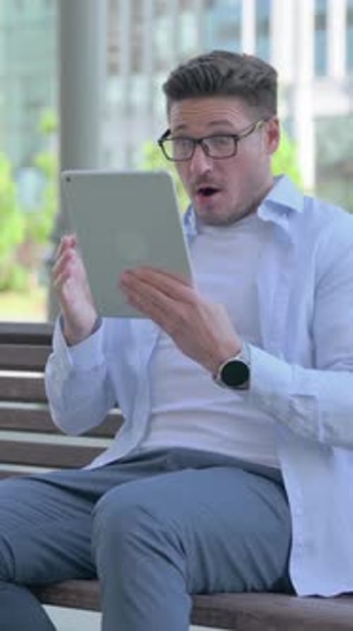 Surprised Man Using Tablet on Park Bench