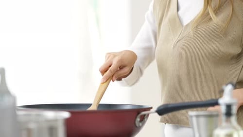 Cooking in Kitchen with Wooden Spoon and Pan