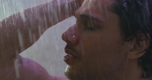 Close up of an young handsome man is taking a hot relaxing shower in a luxury wellness center.