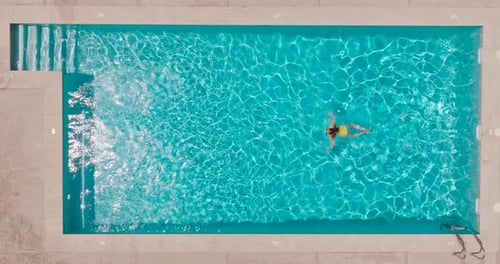 Aerial View of a Woman in Yellow Swimsuit Swimming in the Pool
