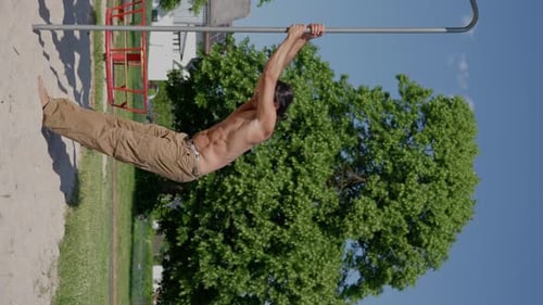 Shirtless Man Doing a Pull Up Outdoors