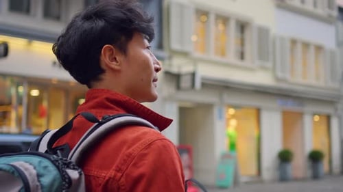 Asian attractive man backpacker walking around beautiful road in city.