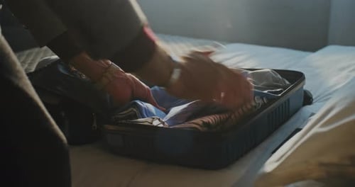 Man Carefully Packing Luggage Before Checking Out of Hotel
