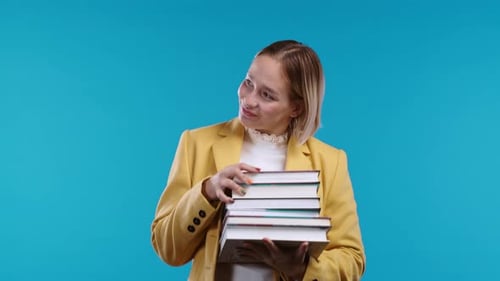 Clever Student Holds Stack of University Books From College Library on Blue Background
