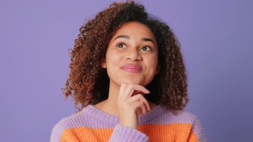 Close-up of smiling woman choosing, making decision looking at camera on lilac background in studio
