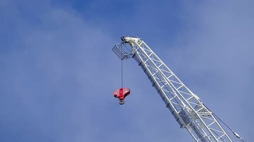 Crane and hook close up with blue sky and moving clouds in the background