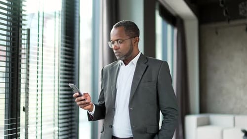 Man in Suit Using Smartphone Indoors