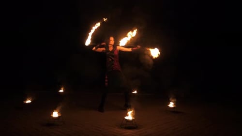 Performer Skillfully Juggling Flaming Torches at Night