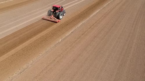 Tractor at work, prepares the field for planting seeds. Aerial view.
