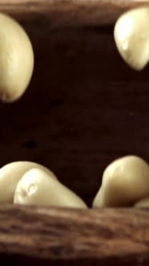 Peeled Garlic Falls Into a Wooden Plate Filmed on a Highspeed Camera at 1000 Fps