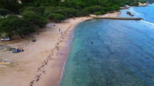 Aerial view of white sandy beach with tourists, blue sea water