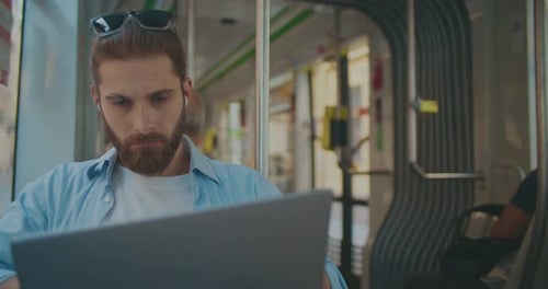 Junger professioneller Programmierer sitzt auf einem Sitz und benutzt Laptop Schöner männlicher Freelancer nachdenklich