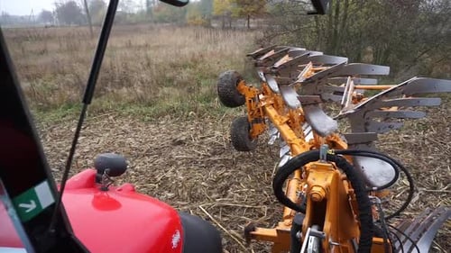 Red tractor plowing the field in Ukraine