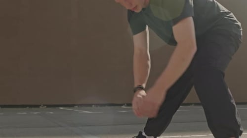 Man Stretches Outdoors Against Wall Before Workout