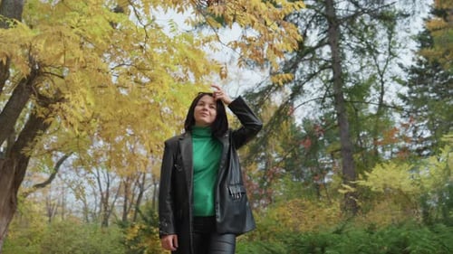 Woman Walking in Autumn Park Touching Her Hair