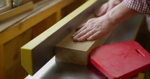 Man Smoothing Wood on Workbench Indoors