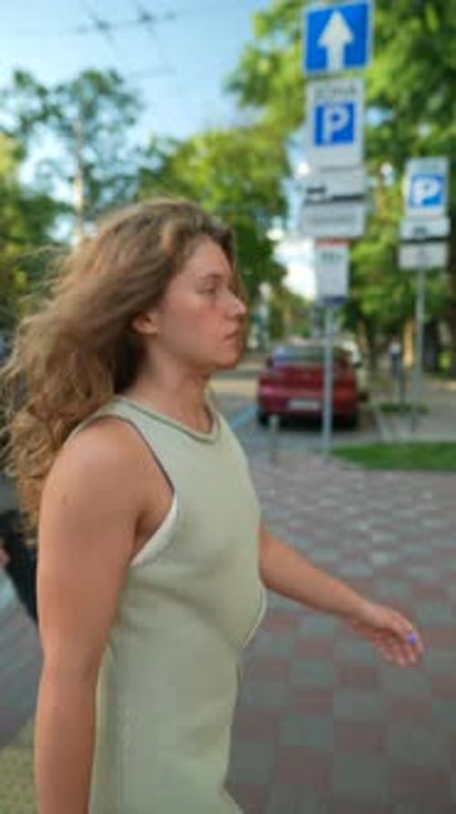 With Her Curly Hair and an Athletic Vibe a Young Girl Walks Through the City on a Summer Day
