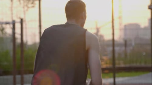 Basketball player practicing dribbling shooting skills at home court during sunset