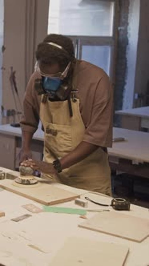 Man Smoothing Wood with Power Sander in Workshop