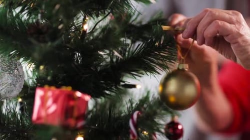 Senior Hands Decorating Christmas Tree with Ornament