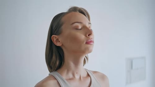 Woman Breathing Deeply Indoors in Front of Wall