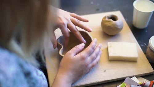 Young woman's hands crafting a bowl with clay on a pottery workshop