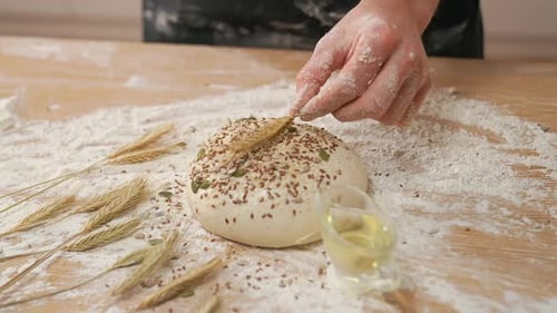 Baker Decorates Seeded Dough Ball with Wheat Stalk