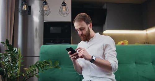 Man Using Smartphone on Couch at Home