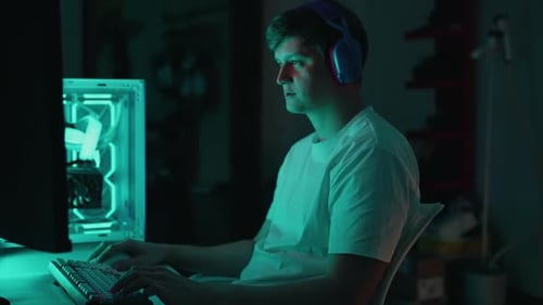 Man Gaming at Computer Desk in Dark Room