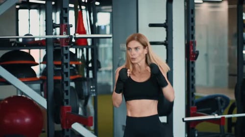Frau trainiert im Fitnessstudio und übt Boxtechniken mit Fokus und Energie