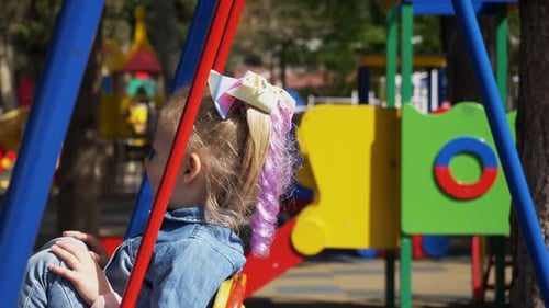 Little Girl on Swing Set at Playground