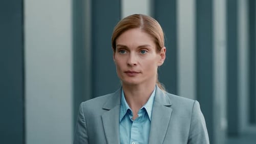 Geschäftsfrau geht tagsüber in einer städtischen Umgebung vor einem modernen Gebäude spazieren