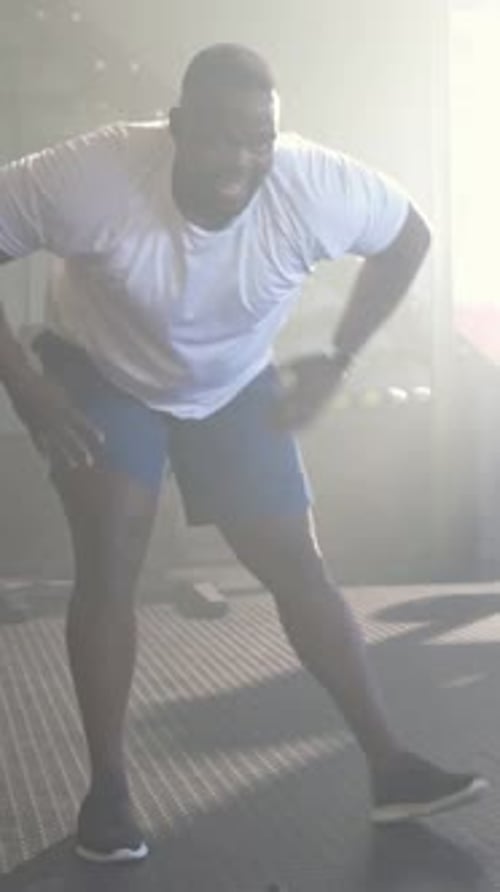 Vidéo verticale : Cordes de combat agrippantes, homme en forme balançant des vagues rapides pour faire du cardio au gymnase, t-shirt blanc