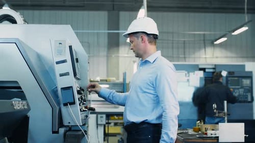 Engineer is Setting Up CNC Lathe Machine on Factory