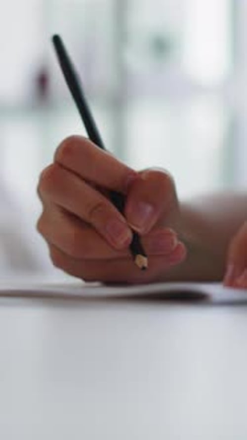 Hands of Woman Drawing with Black Pencil in Exercise Book