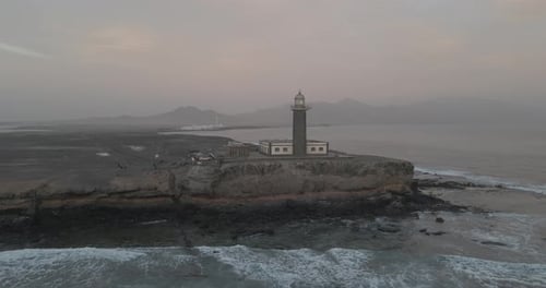 From a mesmerizing bird's eye view, witness a lighthouse perched on a cliff edge. Captivating sight