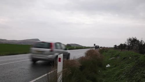 Zwei Autos fahren an einer Straße in der Natur vorbei. Das Wetter ist launisch und zurückhaltend
.