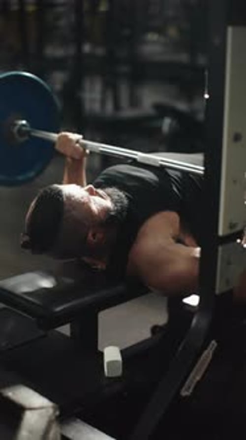 Muscular Bodybuilder Lifting Heavy Barbell During Bench Press Showcasing Physical Power and Fitness