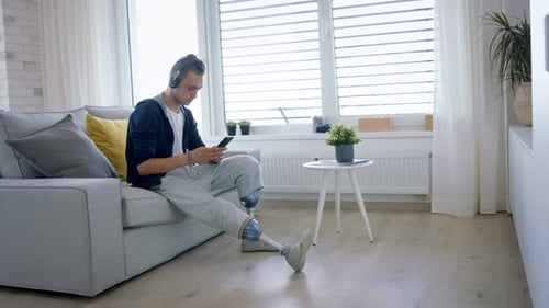 Man with prosthetic leg sits and uses phone