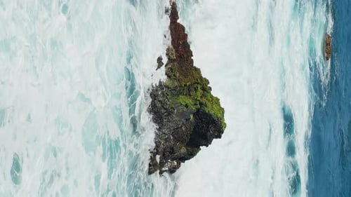 Splashes of water swallowing the rock in the middle of the sea in Tenerife, Spain, vertical static c