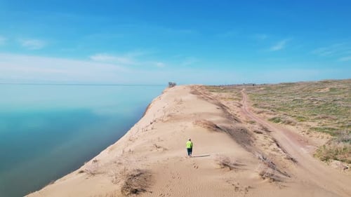 Woman at Desert Dune with Blue Sea at Sunrise